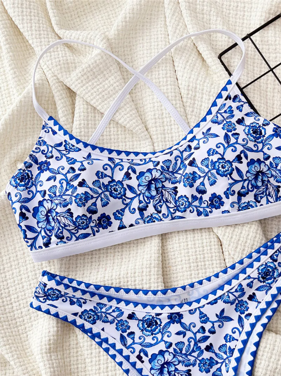 Blue and white floral bikini set flat lay with crop top and cheeky high-leg bottoms.