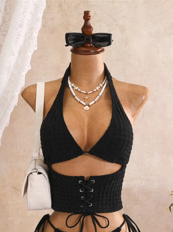 Close-up of black textured halter bodice with plunging neckline, shell jewellery styling and lace-up waist panel.
