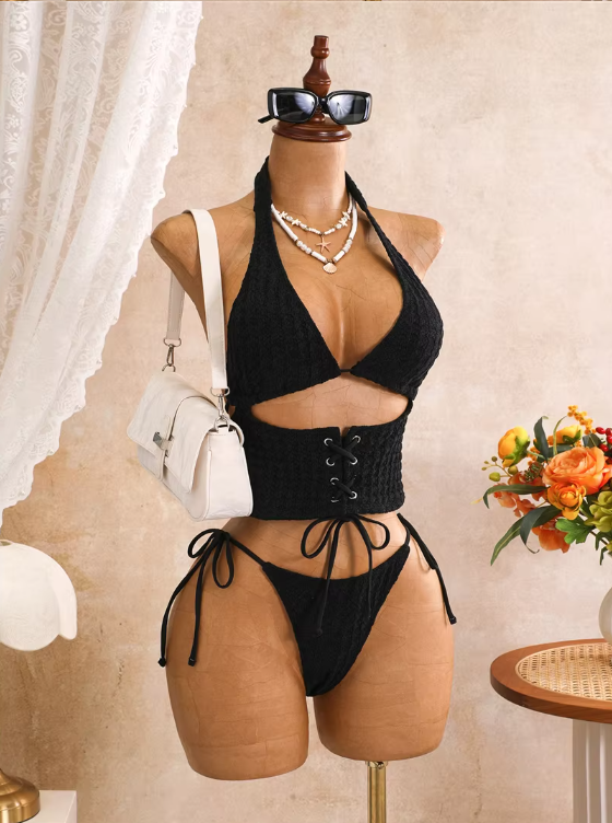Angled front view of black corset-inspired bikini set with halter bodice, front cut-out and lace-up waist detail.