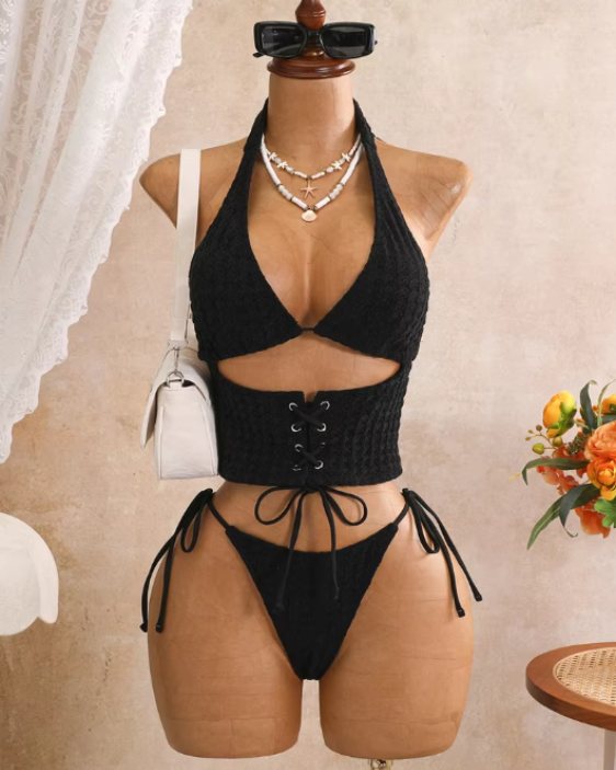Black textured halter bikini set displayed on mannequin with lace-up waist panel and tie-side bottoms.