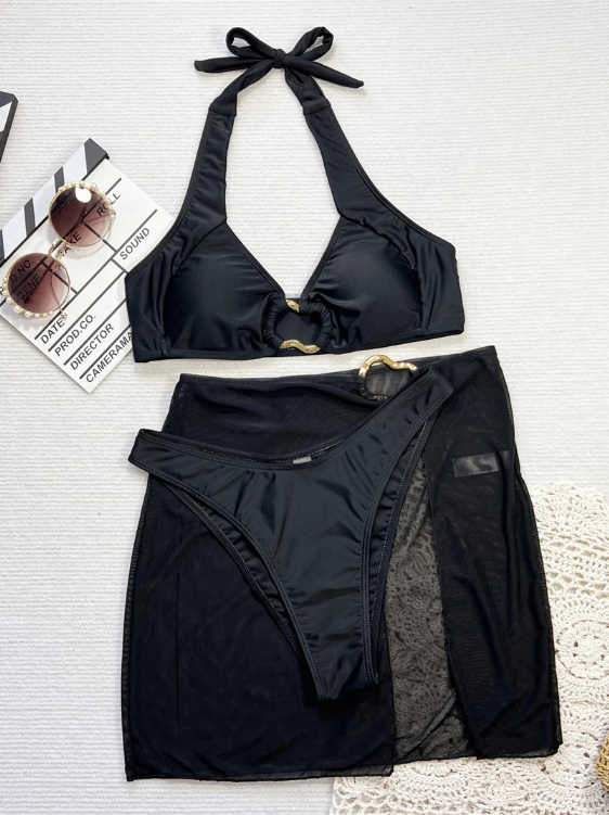 Black halter bikini and matching sheer sarong set with gold-tone ring hardware in a flat lay.