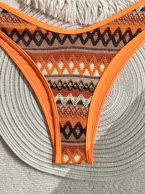Close-up of orange geometric bikini bottoms with high-leg cut and bright contrast trim.