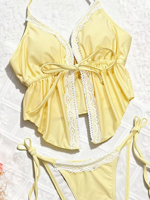 Close-up of yellow tankini set with white lace trim, front tie bodice and coordinating tie-side bikini bottoms.