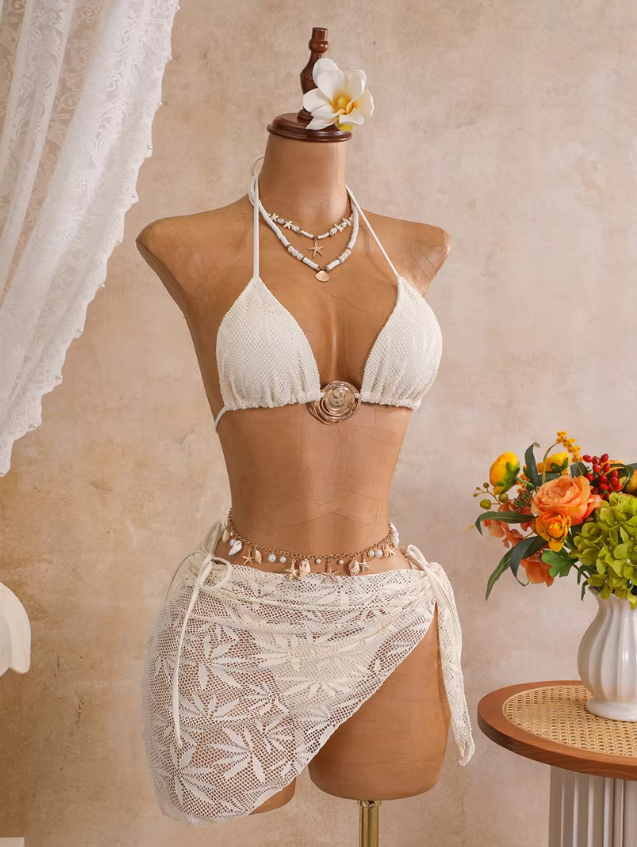 Angled front view of ivory openwork bikini and matching wrap sarong with gold-tone centre hardware.