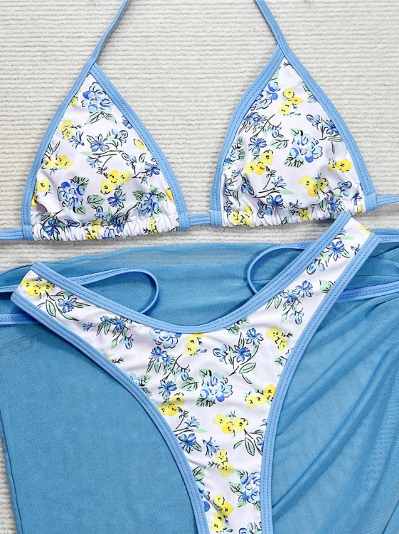 Close-up of blue and yellow floral triangle bikini with sky-blue trim and sheer sarong.