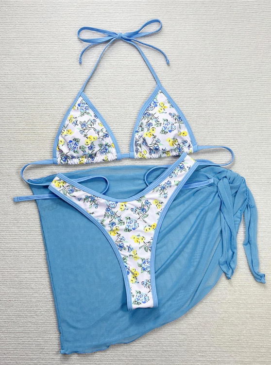 Close-up of blue and yellow floral triangle bikini with sky-blue trim and sheer sarong.