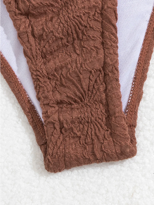 Close-up detail view of chocolate brown textured bikini bottoms showing the crinkled fabric and front shape.
