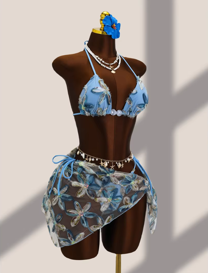 Angled front view of aqua floral bikini and sheer wrap sarong set with dimensional appliqué and tie-side detailing.