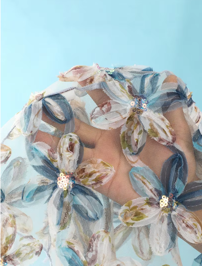 Close-up of aqua sheer mesh fabric with blue dimensional floral appliqué and sequin-centred petal detailing.