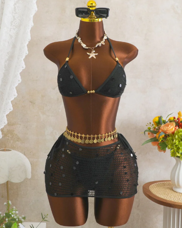 Black crochet-look bikini and sheer mini skirt set displayed on mannequin with sequin embellishment and gold-tone bead accents.