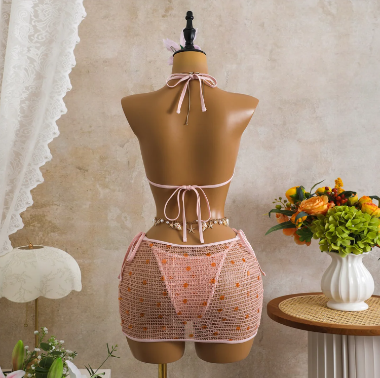 Back view of pink crochet-look bikini and sheer mini skirt set with halter tie, back tie and open-knit skirt.