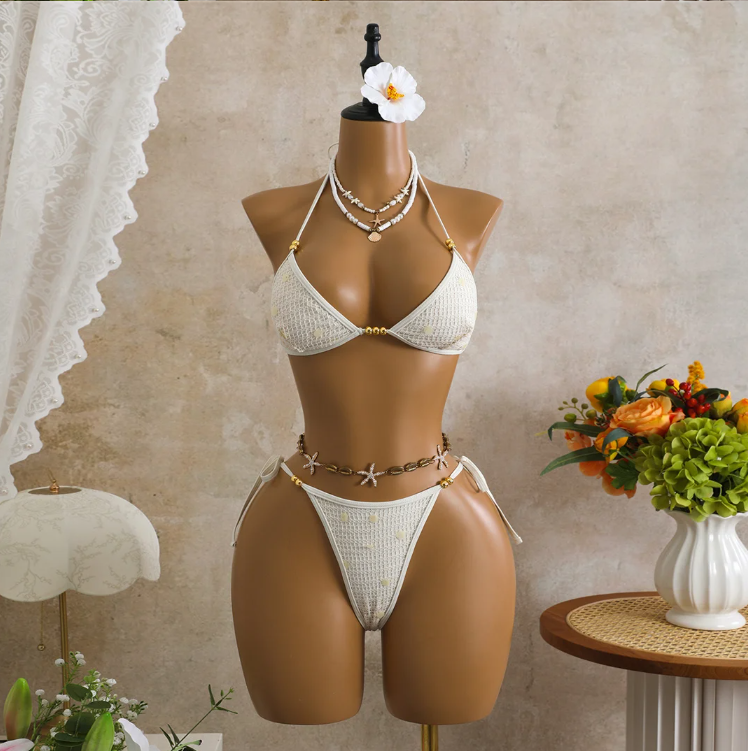 White crochet-look triangle bikini set with sequin embellishment, gold-tone bead accents and tie-side bottoms on mannequin.