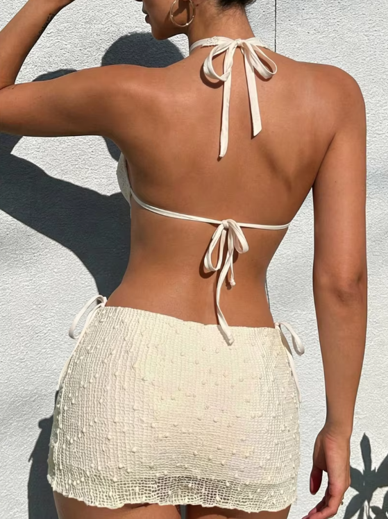 Back view of cream textured tankini set with halter tie top and side-tie mini skirted bottom.